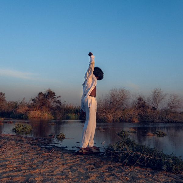 Person stretching outdoors with a serene landscape in the background.